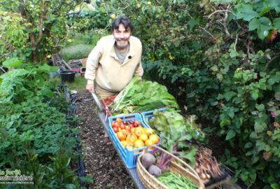 Frank Nathie poussant une brouette débordant de fruits et légumes
