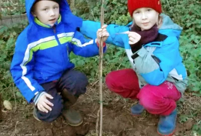 deux enfants plantent un arbre en hiver
